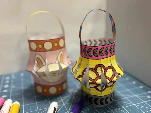 Two hand-coloured paper lanterns with cut sides and woven handles