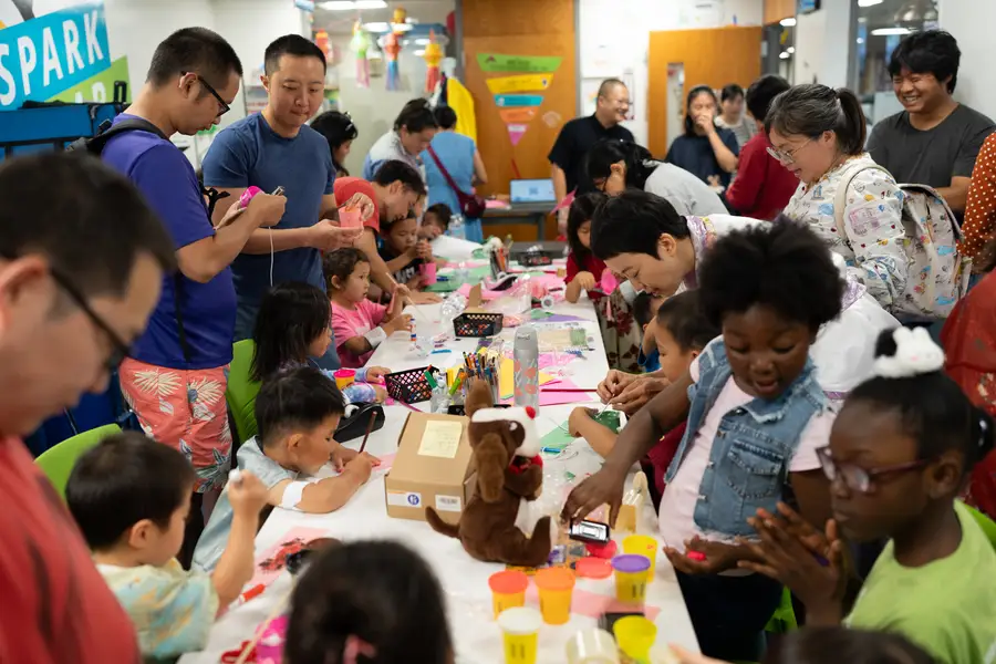 Families with young children gathered around craft tables at a BrightUp Kids mid-autumn community event