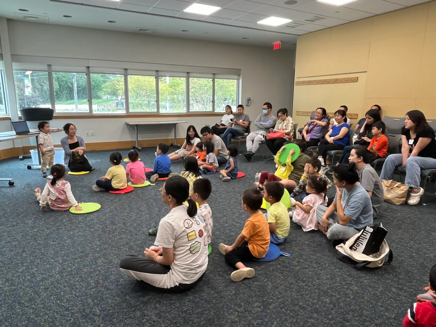 Children and parents seated together on the floor during a BrightUp Kids Mandarin story session at a public library
