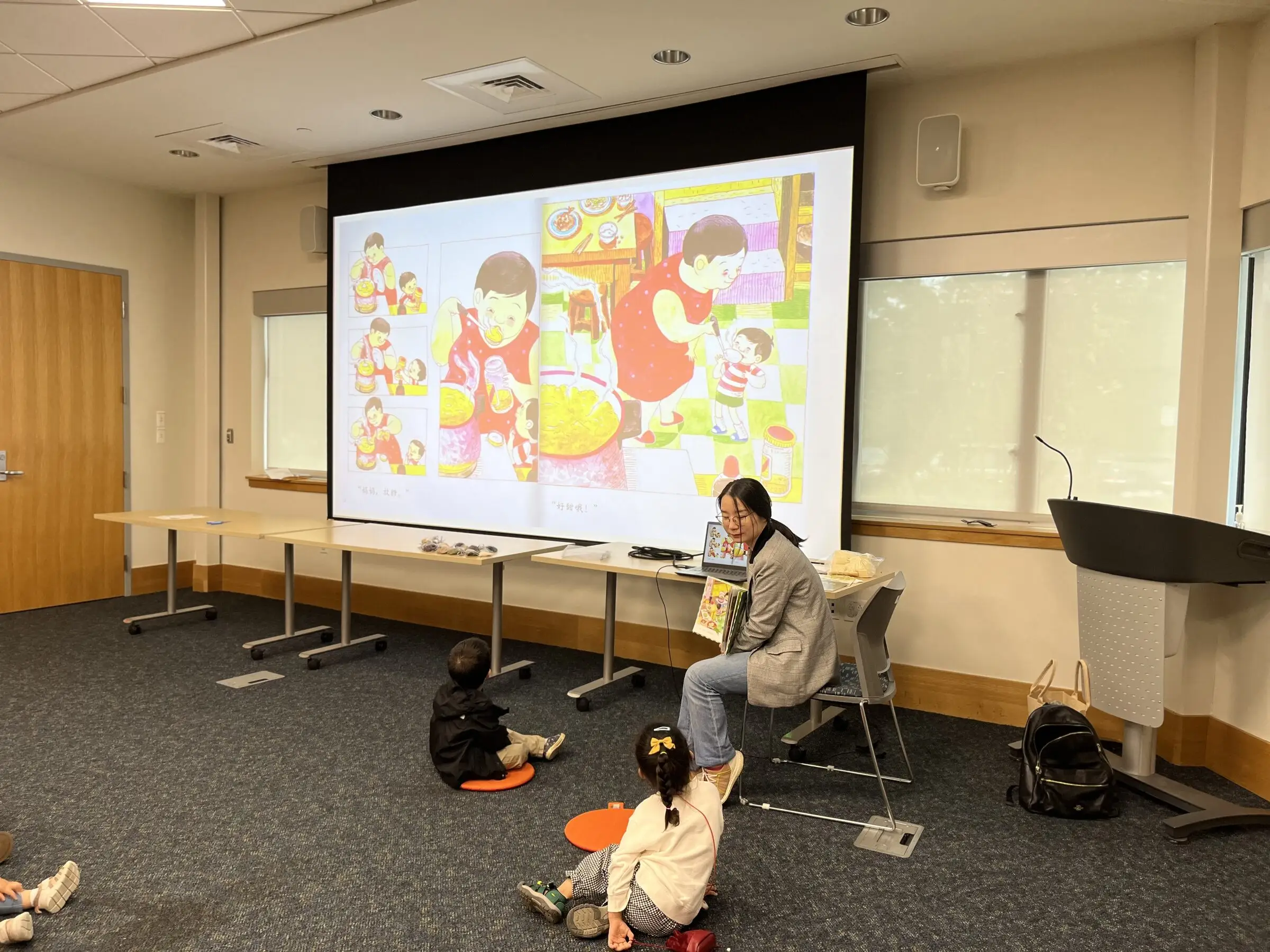 A story leader reads beside a projected Mandarin picture book at a library story time session